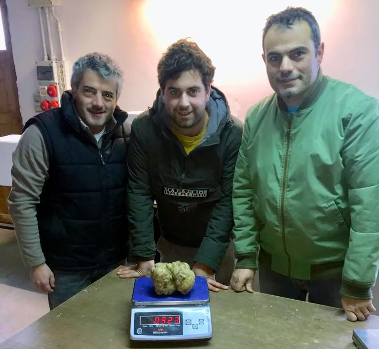 Il team di Cagnasso Tartufi con un tartufo bianco sulla bilancia
